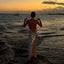 Woman in a white dress standing in the water at sunset