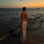 Woman in a sparkly dress standing on a beach at sunset