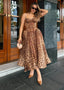 Woman in a leopard print dress standing in front of a building entrance.