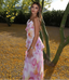 Woman in a floral dress standing next to a tree with yellow flowers