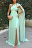 Woman wearing a light green one-shoulder dress with a slit, standing against a textured wall.