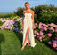 Woman in a white strapless dress standing in a garden with pink and purple flowers and a blue sky.