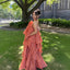 Woman in a coral dress standing on grass with a building in the background