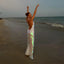 Woman in a glowing dress on a beach at sunset