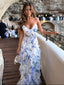 Woman in a floral dress standing on a balcony with a stone wall and people in the background.