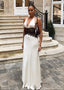 Woman in a white and black dress standing on a stone staircase in an urban setting.