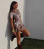 Woman wearing a sparkling silver dress against a plain wall.